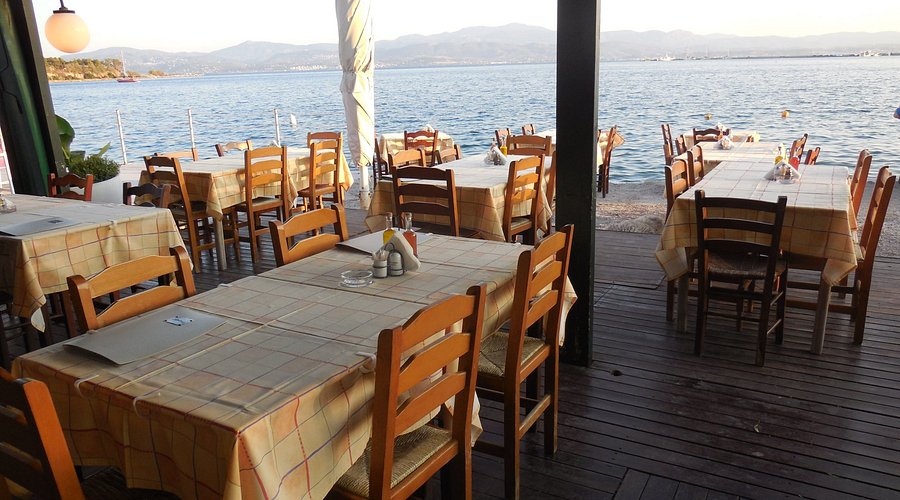Τραπεζάκια εστιατορίου στη Χαλκίδα τοποθετημένα πάνω στο νερό, με φόντο τον Ευβοϊκό