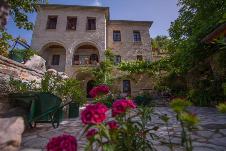 Αυλή με λουλούδια και παραδοσιακό πετρόχτιστο αρχοντικό — δείγμα από τα καλύτερα ξενοδοχεία στον Νομό Ιωαννίνων