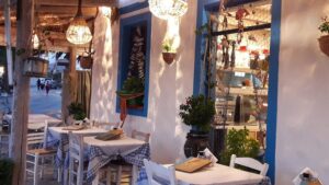 Εξωτερικός χώρος παραδοσιακού εστιατορίου με λευκούς τοίχους και μπλε παράθυρα στην Κάρπαθο