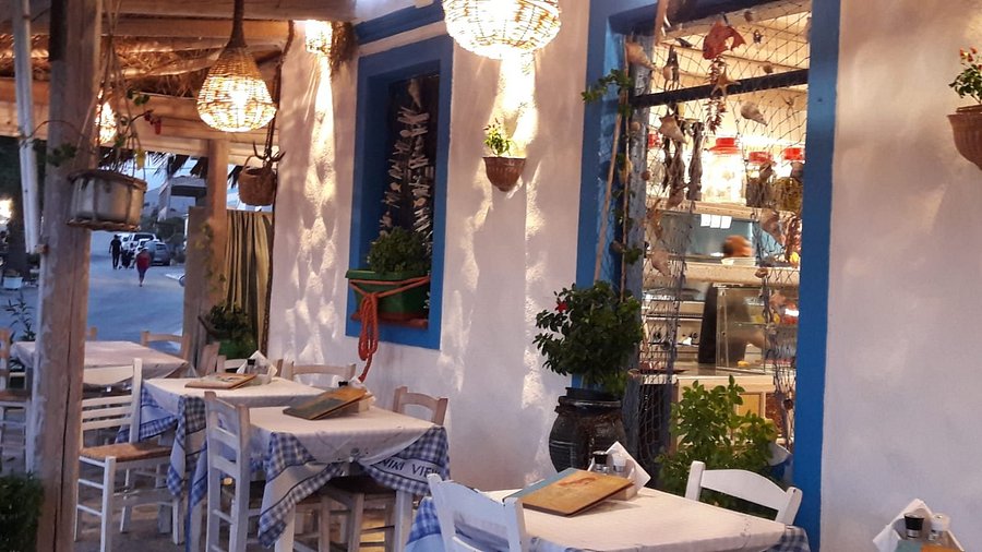 Εξωτερικός χώρος παραδοσιακού εστιατορίου με λευκούς τοίχους και μπλε παράθυρα στην Κάρπαθο