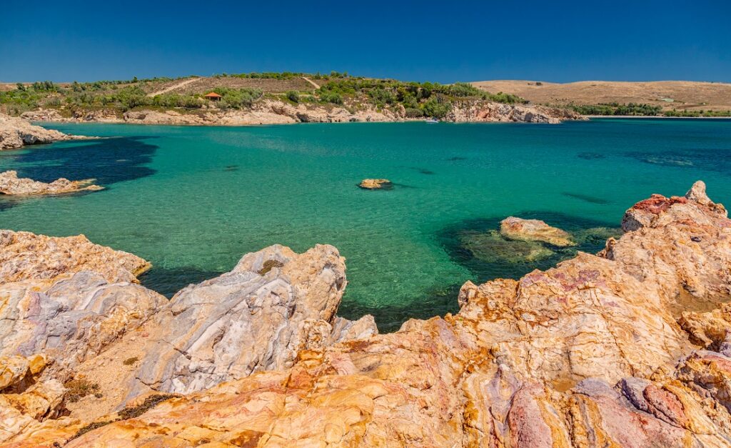 Βραχώδης παραλία στη Λήμνο με γαλαζοπράσινα νερά και άγρια φυσική ομορφιά